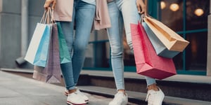 Two people standing outside of a retail store hold shopping bags