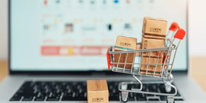 Miniature shopping cart with boxes on a laptop keyboard